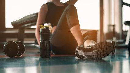 Fototapeta premium Healthy women are sitting and relaxing after exercising with whey protein after workouts at the indoor gym.