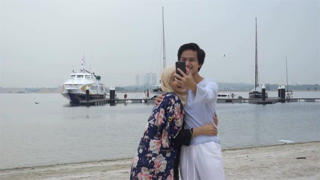 Romantic Couple Taking Photos With Ship Background - Pan Left To Right 
