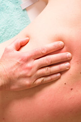 Detail of hands massaging back of a person