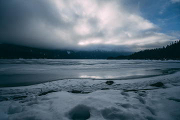 Gefrorener See mit Steinen und Wald