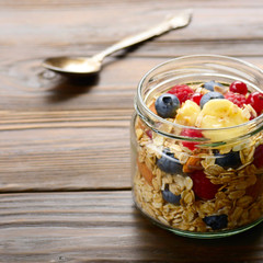 Fruit muesli in glass jar on kitchen wooden table
