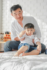Asian Japanese Family father son wearing white shirt carrying child posing for photo on bedroom in white room.To keep memories moment cuteness of son in childhood lifestyle happy