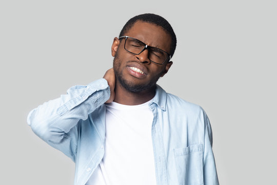 African unhealthy guy suffers from stiff neck studio shot