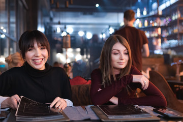 Women in caffee choosing food for an order. Both are smiling and happy of meeting each other.