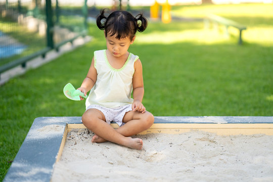 Cute little girl playing at sand box at playground. 