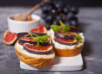Sandwich with cream cheese, figs, honey served on the white cutboard on the concrete background. Healthy food concept