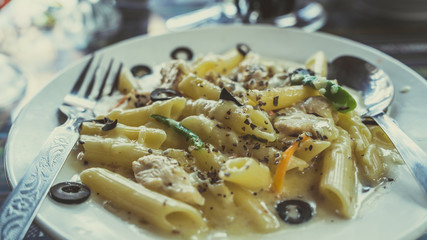 Yummy pasta on cafe table. Closeup plate with portion of tasty pasta with cream sauce placed on...