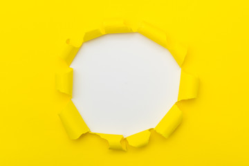Yellow paper with ripped hole white color in the middle background, flat lay