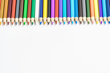 Group of mixed colourful pencils arranged in line and isolated on white, children school or office suppliers photographed with soft focus from side view, with space for text