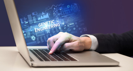 Businessman working on laptop with GENETIC ENGINEERING inscription, cyber technology concept