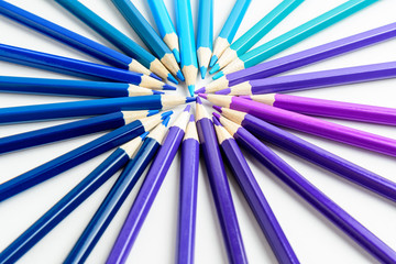 Mixed light and dark blue, purple, cyan and teal colored pencils in circle,  isolated on white, children school or office suppliers photographed with soft focus from side view, with copy space