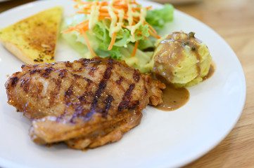 Top view grilled chicken steak set in white dish on wooden table background.Chicken grill, mashed potato, bread and salad.Restaurant menu.