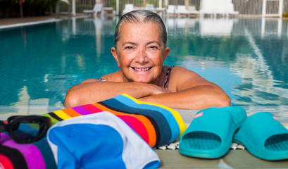 Attractive senior woman enjoys the swimming pool. Outdoor pool with blue water. Healthy activity to...