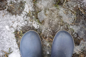 Person in boots standing on on melted snow