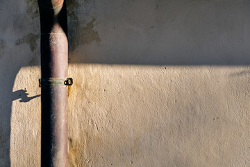 Old rain gutter downpipe on a sunny wall of a house in Germany