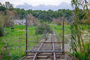 Closed railway lines with barbed wire at a field.