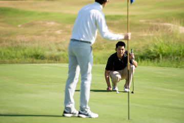 Obraz premium Two Asian man golfer aiming golf ball at golf course