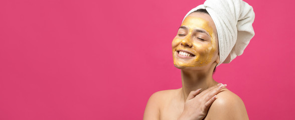 Beauty portrait of woman in white towel on head with gold nourishing mask on face. Skincare cleansing eco organic cosmetic spa relax concept.