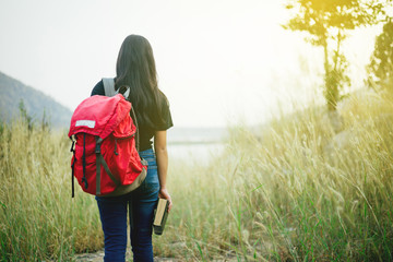 Woman with backpack standing in field holding a bible,mission concept.