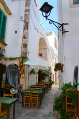Street in Locorotondo town, Italy, region of Apulia, Adriatic Sea - a reastaurant awaiting first guests for lunch