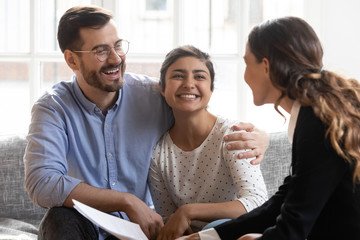 Excited international couple talking with female realtor at meeting