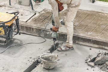 Construction worker using jackhammer drilling concrete surface