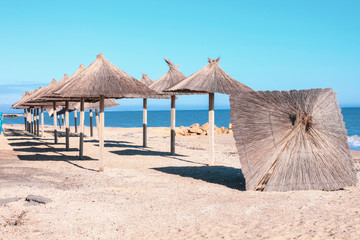 Straw umbrellas, blue sea water and sky background. South beach scenic landscape wallpaper, summer vacation season concept.Vivid blue sea with blurred copy space.Social media banner,resort advertising