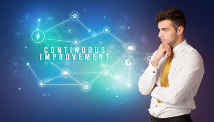 Businessman in front of cloud service icons with CONTINUOUS IMPROVEMENT inscription, modern technology concept