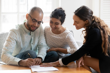Happy multiracial couple closing deal with female broker