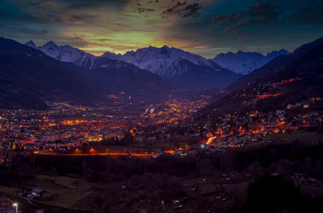 Fototapeta premium Panorama of Aosta city at sunset, with mountains on background and colorfull sky