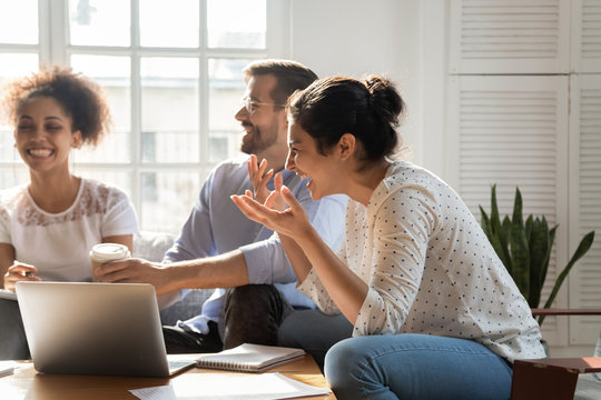 Overjoyed multiethnic employees have fun brainstorming indoors
