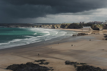 Beach with people just before big storm. Dark sky in the background.