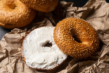 Sesame bagels with spreadable cream cheese on dark background
