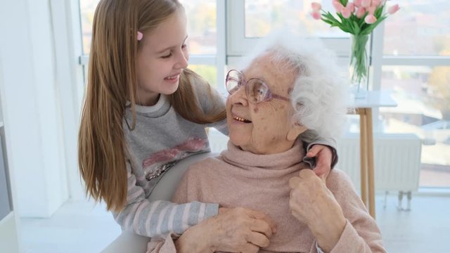 Tender hugs of granddaughter and grandmother at home
