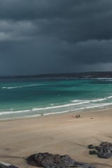Stormy, dark sky over the beach with groups of people
