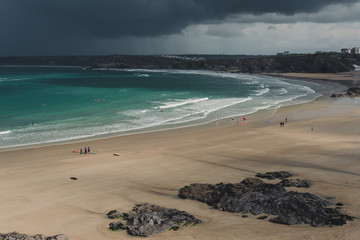 Large beach with groups of people and stormy sky