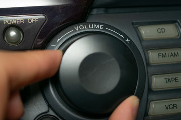 A person turning the volume wheel up or down (the focus is on the word "volume" written on the device)