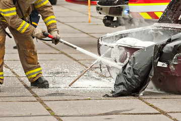 The fireman extinguishes the burned car. Training firefighters. Demonstration rescue work.