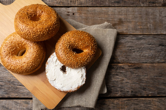 Sesame bagels with spreadable cream cheese on wooden background