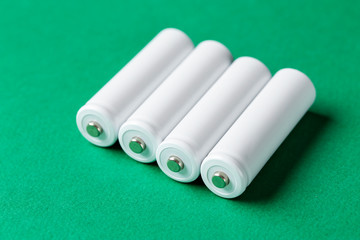 White size AA batteries on a green background top view.