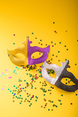 A festive, colorful group of mardi gras or carnivale mask on a yellow purple background. Venetian masks.
