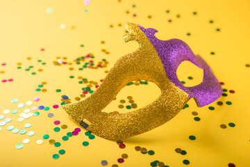 A festive, colorful group of mardi gras or carnivale mask on a yellow purple background. Venetian masks.