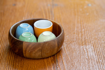 Obraz na płótnie Canvas colorful ceramic cups in wooden bowl.