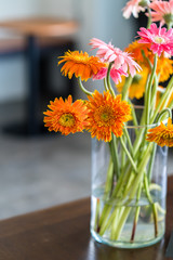 Blossom Gerbera in grass vase on wooden table.