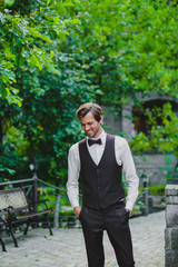 Handsome young bridegroom posing on the territory of country hotel