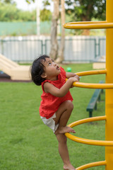 Cute asian girl playing at playground in summer.