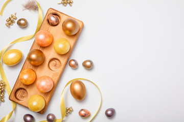 Colorful pastel Easter eggs background with gold and orange eggs. Top-down view, flat lay