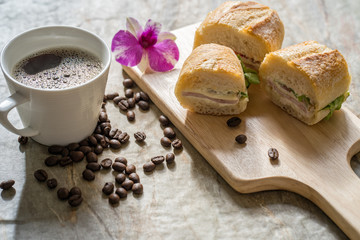 Obraz na płótnie Canvas ham cheese baguette, cup coffee on textured tile table.