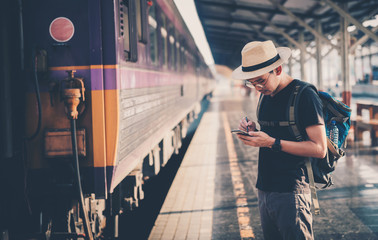 Fototapeta premium A picture of an independent Asian man working at a train station before traveling. Work and travel concepts