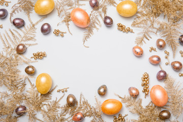 Easter eggs decorations with flower branches and bird feather on pastel blue table. Top view, flat lay